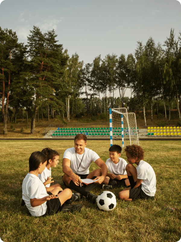 Coach discussing strategy with youth soccer team outdoors.